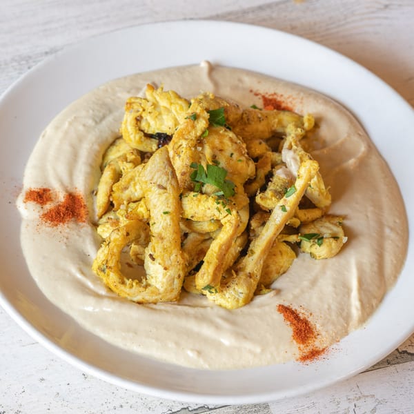 Baba Pita's chicken shawarma, seasoned and served over creamy hummus with paprika and parsley.