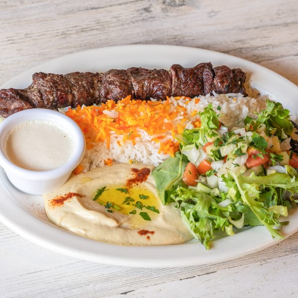 Baba Pita's Mediterranean plate with beef kebab, rice, hummus, a side salad, and white sauce.