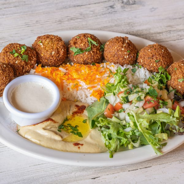 Baba Pita's falafel plate with hummus, rice, salad, and tahini sauce on a white plate.