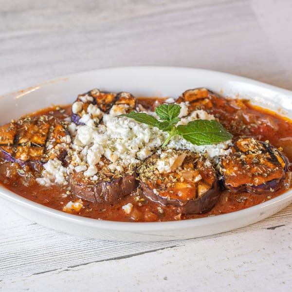 Baba Pita's Mediterranean eggplant dish with tomato sauce, feta cheese, and mint garnish.